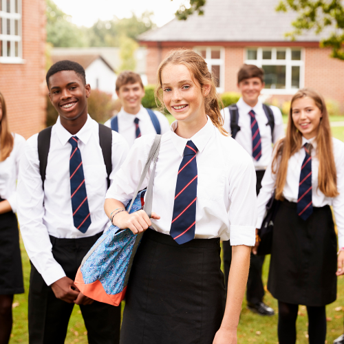 Group of students in school uniforms standing outdoors with a building in the background